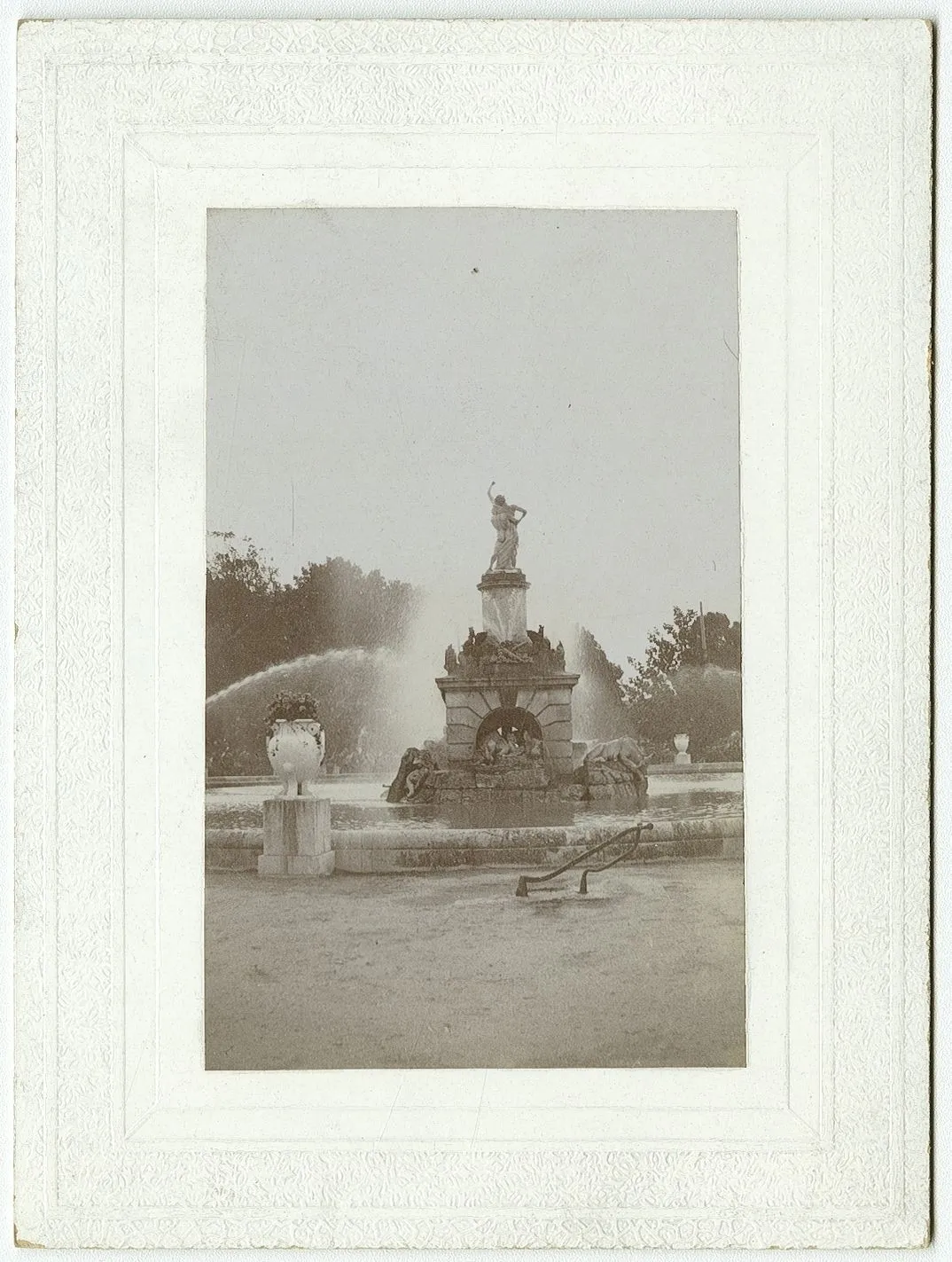 Fotografía antigua enmarcada de una fuente con estatua y surtidores de agua.