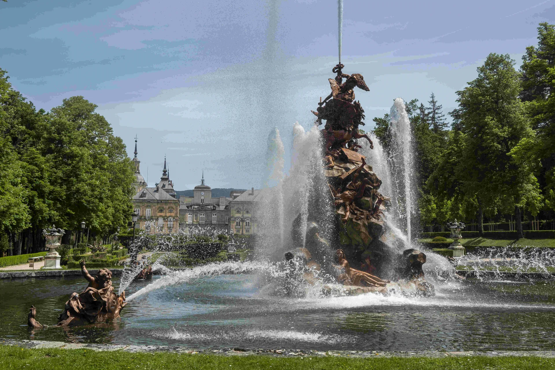 Fotografía de la Fuente de la Fama con los juegos de agua y la fachada de Palacio al fondo.