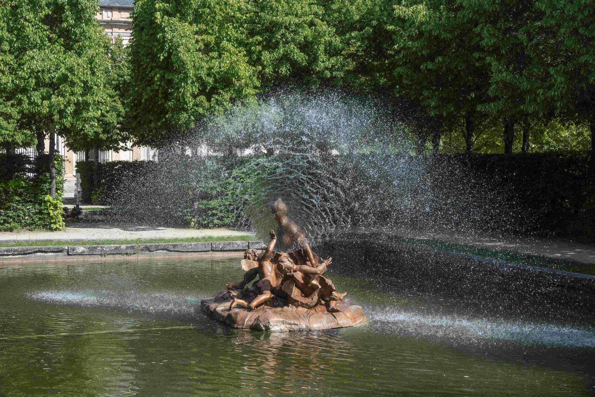 Fuente con una escultura central femenina acompañada de dos céfiros que juegan con un surtidor de agua en forma de abanico.