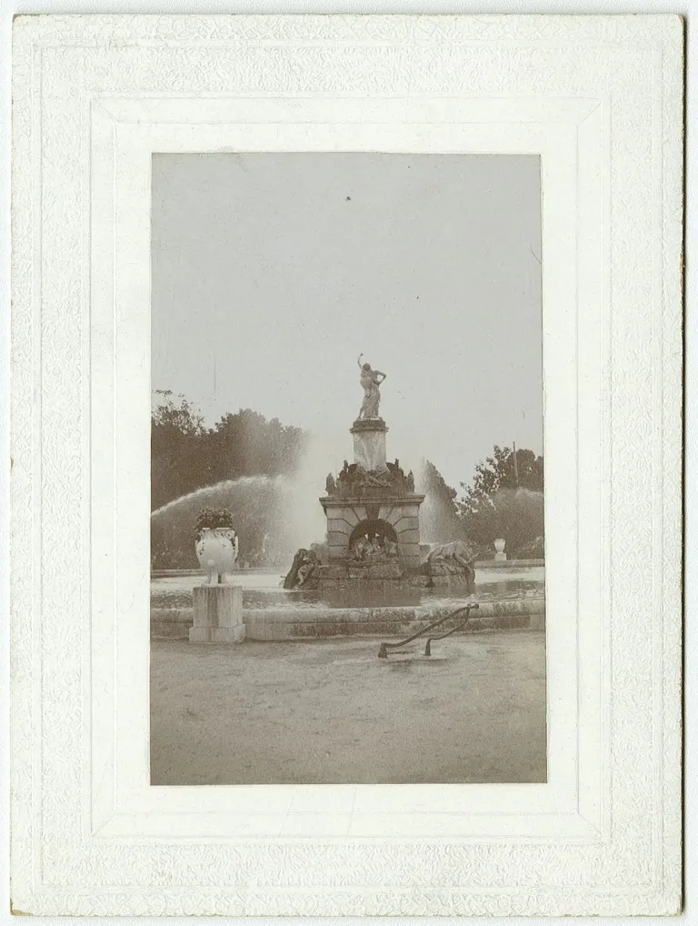 Fotografía antigua enmarcada de una fuente con estatua y surtidores de agua.
