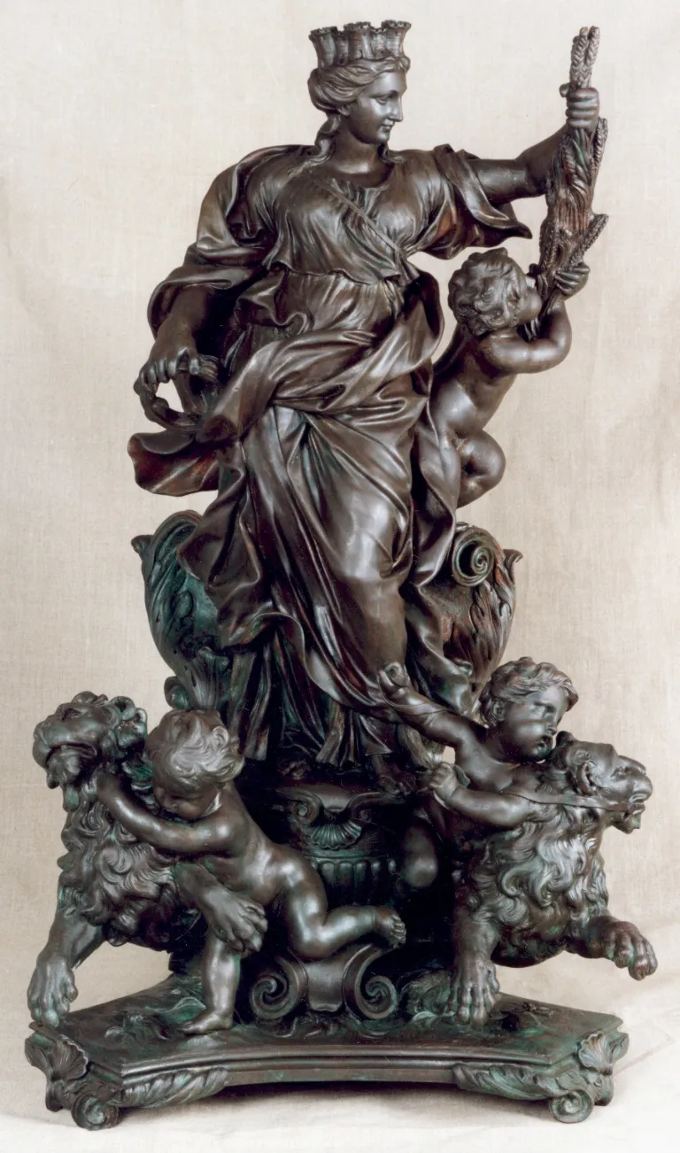 Escultura de bronce de una figura femenina coronada con niños y leones.